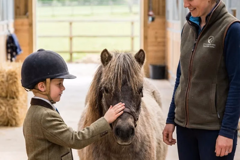 Kind steht ruhig neben einem kleinen Pony und hält den Führstrick locker in der Hand